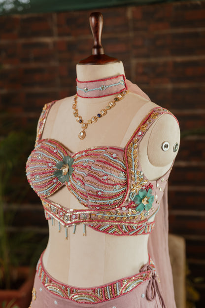 A pink embellished belly dance costume set displayed on a mannequin, featuring a heavily beaded and sequined bra top with a matching waistband and a coordinating necklace.