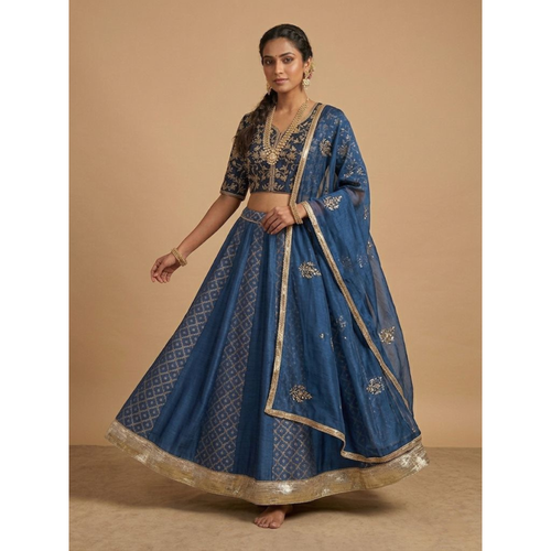Woman wearing a blue embroidered traditional outfit on a beige background