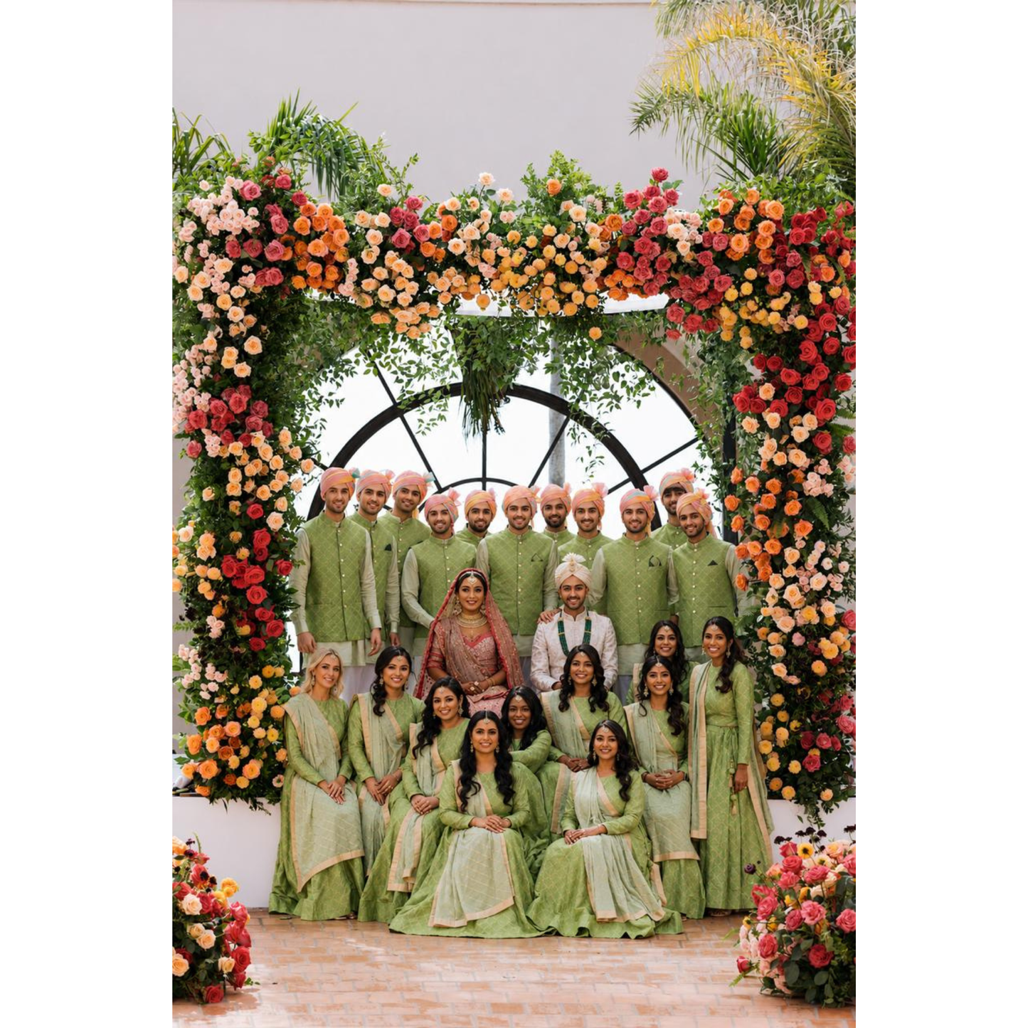 Group of people in formal attire standing in front of a floral arch