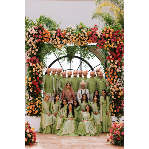 Group of people in formal attire standing in front of a floral arch