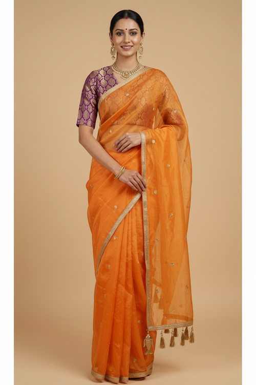 Woman wearing an orange saree with a beige background