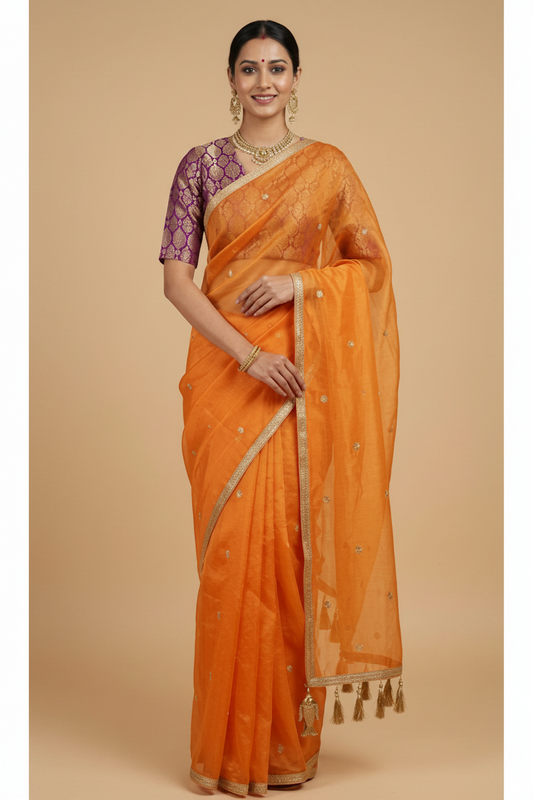 Woman wearing an orange saree with a beige background